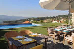 a table with chairs and an umbrella next to a pool at Casas da Li in Arcos de Valdevez