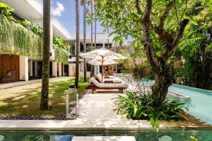 een terras met parasol naast een zwembad bij Villa Zeno Arete Pererenan 6 Bedroom , Ice Bath, Sauna and Gym in Tumbak Bayuh