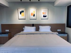 a bedroom with a large bed with four pictures on the wall at The W Residence in Jakarta