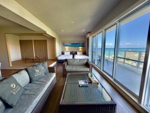 - un salon avec un canapé, un lit et des fenêtres dans l'établissement Coral Palace Onna by Sunset Avenue, à Onna