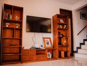 a living room with a television and book shelves at Makinihomestay in Arusha