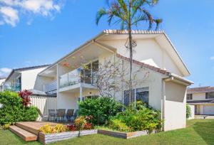 a house with a palm tree in front of it at Isle Of Palms Resort in Gold Coast