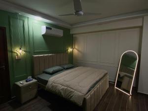 a bedroom with a bed in a green room at Luxury, Modern & Central Apartment Islamabad, with Gym, Near Motorway & Airport in Islamabad