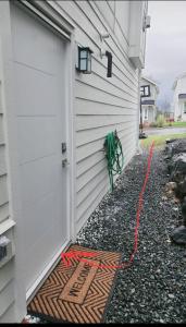 a door with a green hose next to a house at New Langford Suite near Lake & Mall, Free Parking in Goldstream Station