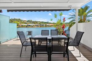 a table and chairs on a deck with a view of the water at Isle Of Palms Resort in Gold Coast