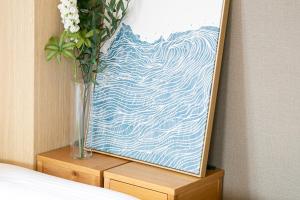 een vaas met bloemen op een tafel met een schilderij bij SG Hotel Kinshai Hakata in Fukuoka