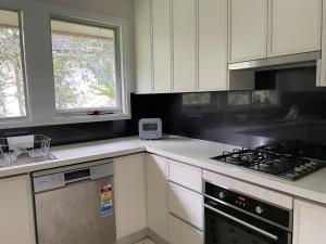 a kitchen with white cabinets and a stove top oven at Bus Mac Uni Mac Centre Bright and Sunny in Sydney
