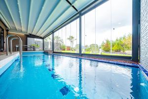 a swimming pool with blue water in a building with windows at Jecheon The Shine Cheongpung in Jecheon