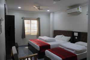 ein Schlafzimmer mit zwei Betten und einem Fenster in der Unterkunft SRG Shivam Residency in Tiruvannāmalai