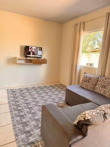 Una sala de estar con un sofá y un televisor en una pared. en Refujo Ideal em Família, en Prado