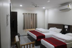 ein Schlafzimmer mit zwei Betten und einem Fenster in der Unterkunft SRG Shivam Residency in Tiruvannāmalai + 2 Fotos