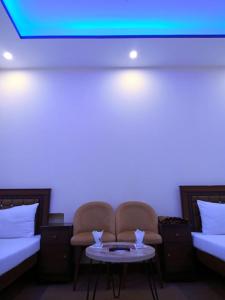 a room with two beds and a chair and a table at Perfect Lodge Guest House in Islamabad
