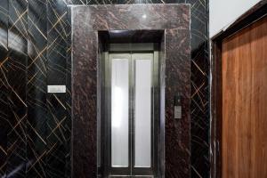 a hallway with a door in a room with black tiles at Townhouse Oak Civil Lines Prayagraj Formerly The Grand Palace in Allāhābād Junction