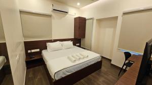 a small room with a bed with two towels on it at Chippy Inn Tharamani in Chennai