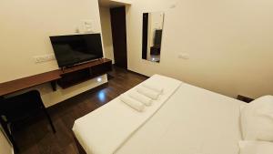 a hotel room with a bed and a flat screen tv at Chippy Inn Tharamani in Chennai