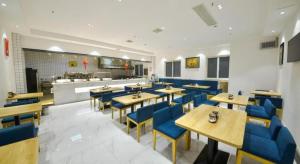 un restaurant avec des tables en bois et des chaises bleues dans l'établissement PAI Hotel·Luoyang Dingding Bei Road Hongjin Logistics International Peony Garden, à Luoyang