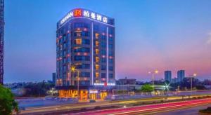 Borrman Hotel Zhanjiang Xuwen Port Terminal في Xuwen: مبنى مرتفع مع لافتة في أعلاه