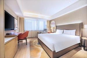 a hotel room with a large white bed and a desk at Echeng Hotel Changsha Evening News in Changsha