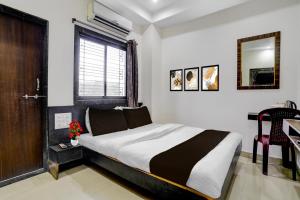 a bedroom with a bed and a desk and a window at Hotel O Sai Teerth Theme Park Formerly Sai Dhanlaxmi in Shirdi +24 photos