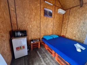 ein Schlafzimmer mit einem blauen Bett und einem kleinen Kühlschrank in der Unterkunft Studio Karenga in La Tontouta