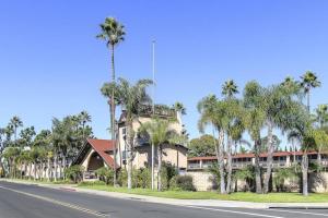 a building on the side of a street with palm trees at Rodeway Inn Carlsbad in Carlsbad