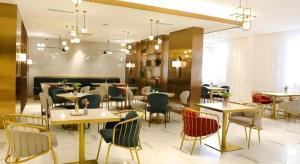 un restaurant avec des tables et des chaises dans une salle dans l'établissement Magnotel Wulanhaote Hanshan Dong Street, à Ulan Hot 41 autres photos