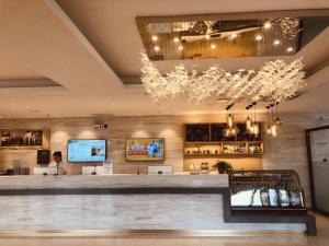 - un hall avec un bar orné d'un lustre dans l'établissement City Comfort Inn Dandong Railway Station Yalu River Scenic Area, à Dandong