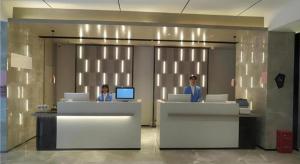 deux femmes assises à un bureau dans un hall dans l'établissement Echarm Hotel Nanchang Bayi Square Metro Station Wushang MALL, à Nanchang