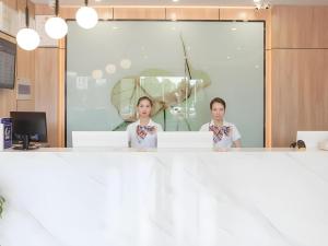 dos mujeres de pie detrás de un mostrador en una habitación en Green Tree Inn Express Hefei Yungu Road Linhu Community, en Hefei