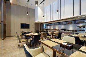 柳州にあるEcharm Hotel Liuzhou Yaobu Ancient Townのテーブルと椅子とキッチンのあるレストラン