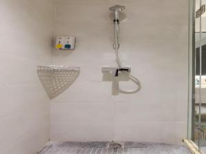 La salle de bains est pourvue d'une douche et d'un mur blanc. dans l'établissement City Comfort Inn Jiyuan Jishui Avenue Jigang, à Jiyuan