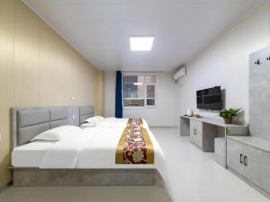 une chambre avec un grand lit et une télévision dans l'établissement GreenTree Apartment Jinan Jiyan Road Shandong Cancer Hospital, à Jinan