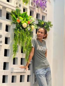 a woman standing in front of a wall with flowers at lalinkan poolvilla 