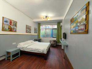 a bedroom with a bed and a desk and a window at Haikou Banana Hostel in Haikou