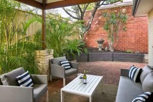 Kingsley Lake House 500Mbps Lakeside Wineries في بيرث: فناء مع كراسي وطاولة مع زجاجة من النبيذ