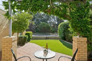 Kingsley Lake House 500Mbps Lakeside Wineries في بيرث: زجاجة من النبيذ موضوعة على طاولة في حديقة