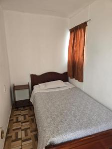 um pequeno quarto com uma cama e uma janela em Hostal Las Cruces II em Arica