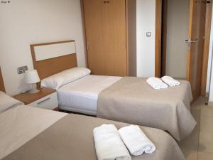 a hotel room with three beds with towels on them at Alicante Mar in Alicante