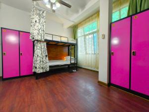 a room with pink doors and a bed in it at Haikou Banana Hostel in Haikou