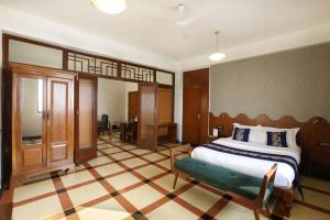 a bedroom with a large bed with a green bench at Sea Green Hotel in Mumbai