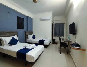 a hotel room with two beds and a table and a chair at Hotel O Rajahmundry Central Railway Station Formerly Sanjeevi Residency in Godāvari