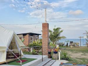 a house with a tent and the ocean in the background at bira pata glamping in Marang