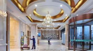 XuanchengにあるVienna Hotel Anhui Xuancheng High-Speed Railway Stationのシャンデリアのあるロビーに立っている二人