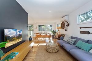 a living room with a blue couch and a tv at Jimmys Beach House in Hawks Nest