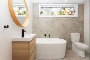 a bathroom with a tub and a toilet and a mirror at Jimmys Beach House in Hawks Nest +17 photos
