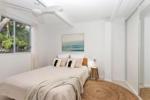 a white bedroom with a bed and a window at Jimmys Beach House in Hawks Nest