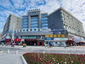 a large building on a city street with people in front at Green Tree Inn Zhuhai International Airport Huafa Shangdu in Baigaonongchang