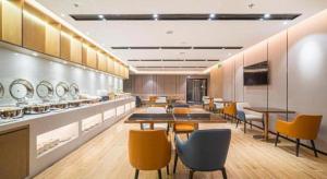 a restaurant with tables and chairs and a cafeteria at Echarm Hotel Nanjing Expo Center Olympic East Metro Station in Nanjing
