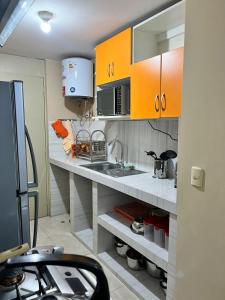 a kitchen with orange cabinets and a sink at bonito departamento cerca al Aeropuerto Jorge Chávez in San Antonio