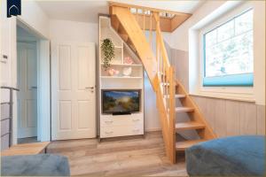 a tiny house with a staircase and a tv at Ferienhaus Glück unter Reet in Zirchow
